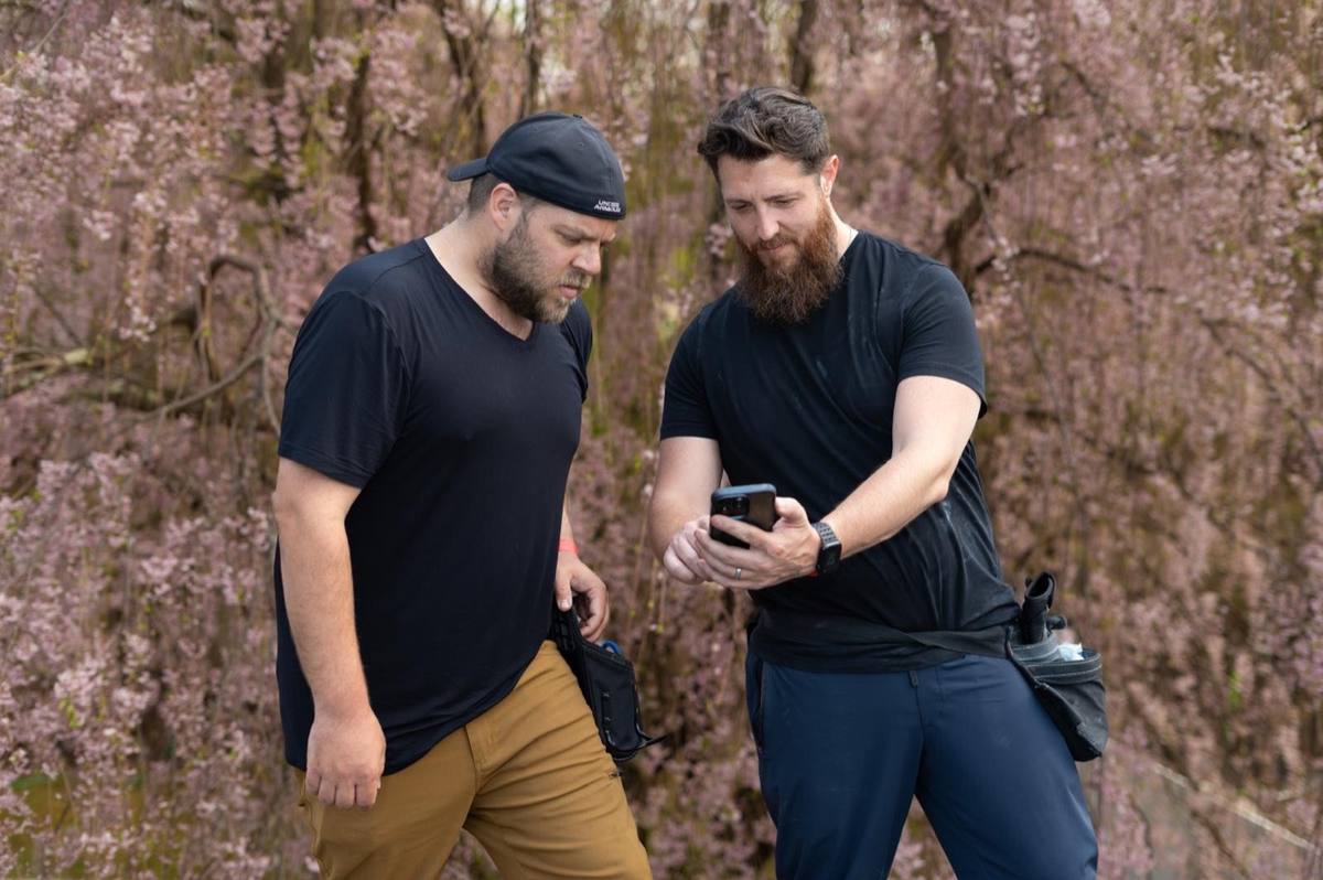 Josh and Drew reviewing a claim on a phone with cherry blossoms in the background