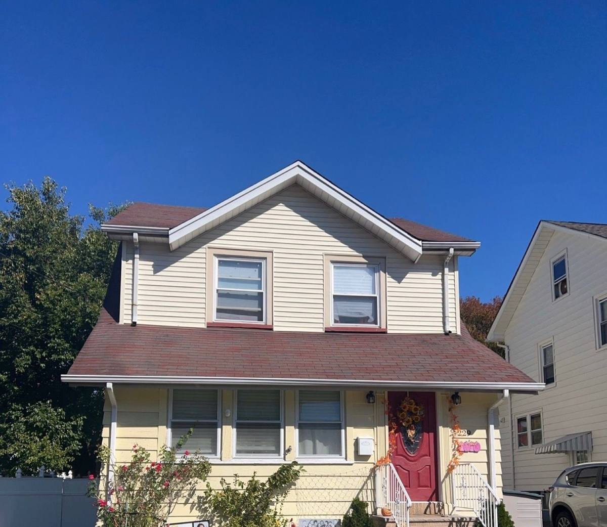 Yellow two-story home with the old roof before replacement