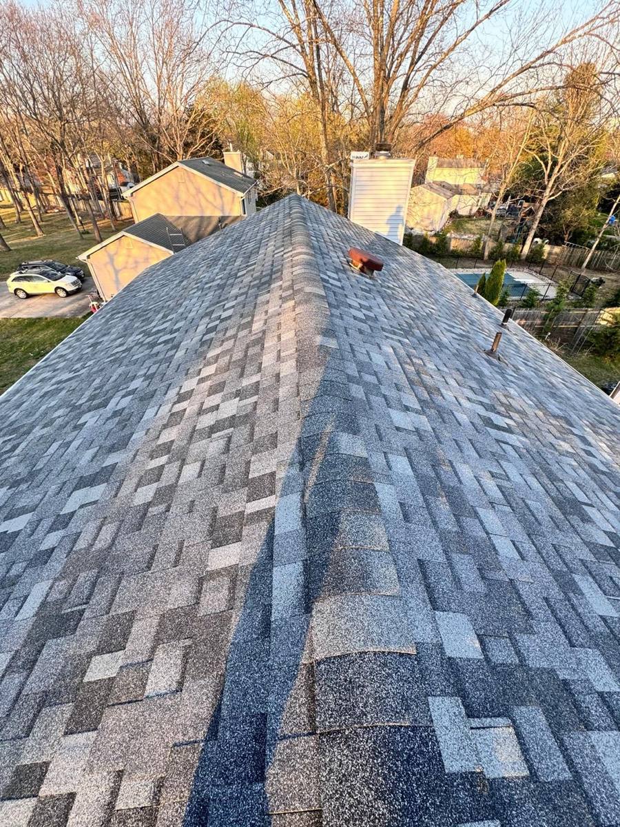 Freshly installed grey shingles with a skylight, crew finishing the job